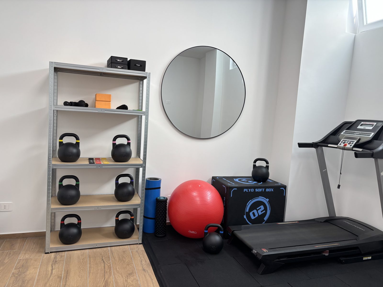 Scaffale kettlebell, plyo box e tapis roulant nella sala allenamento